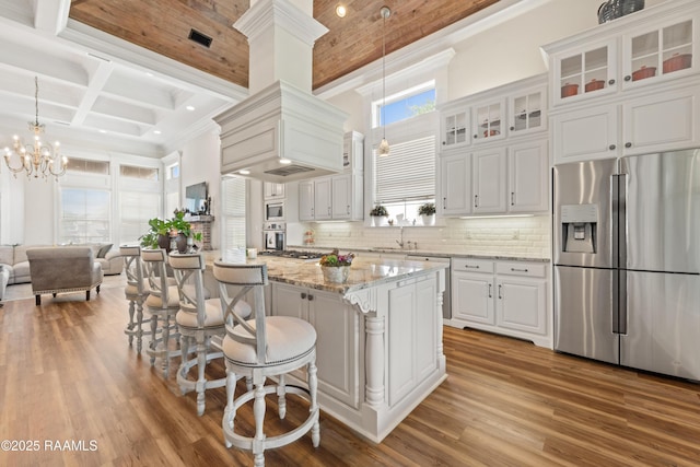 kitchen with white cabinets, stainless steel appliances, wood finished floors, and a chandelier