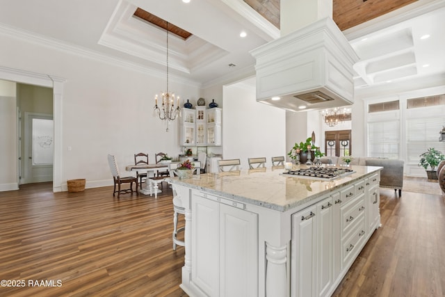 kitchen featuring dark wood-style flooring, a notable chandelier, a kitchen breakfast bar, white cabinetry, and a tray ceiling
