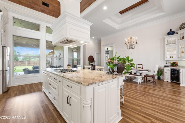 kitchen with a notable chandelier, appliances with stainless steel finishes, beverage cooler, white cabinetry, and dark wood-style floors