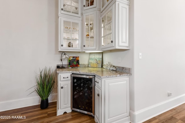 bar featuring beverage cooler, baseboards, dark wood-style flooring, and a bar