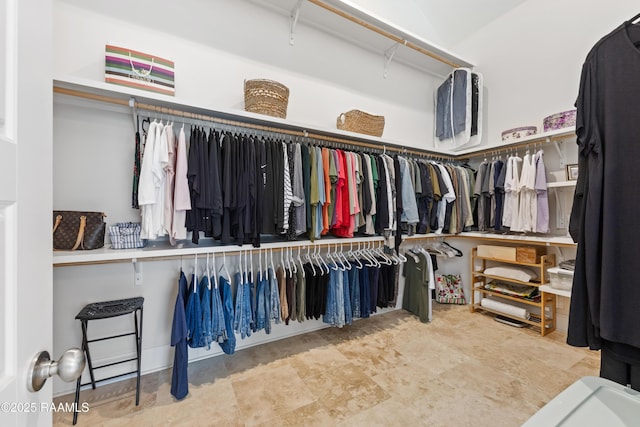 walk in closet featuring stone finish flooring