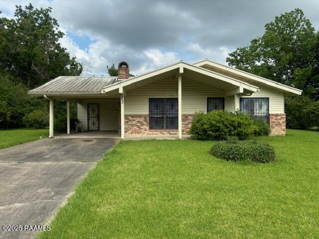 1614 Norway St, Opelousas, LA 70570 - ranch-style home featuring brick siding, a front lawn, a carport, concrete driveway, and a chimney