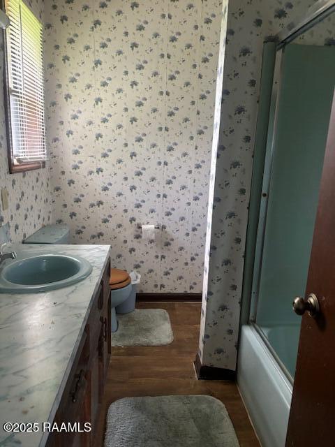1614 Norway St, Opelousas, LA 70570 - full bathroom with wallpapered walls, wood finished floors, baseboards, vanity, and toilet