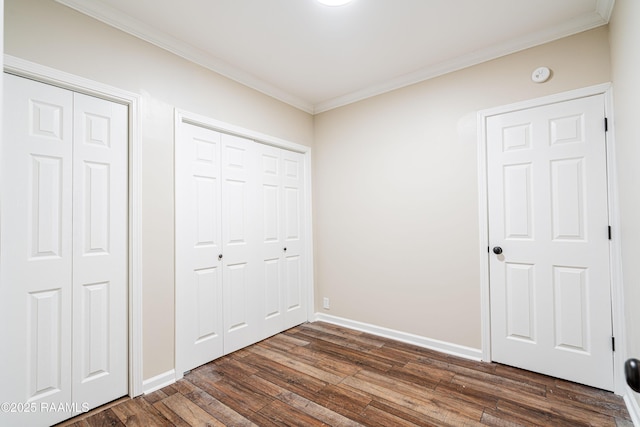 813 S Arenas St, Rayne, LA 70578 - unfurnished bedroom featuring multiple closets, baseboards, ornamental molding, and dark wood-type flooring