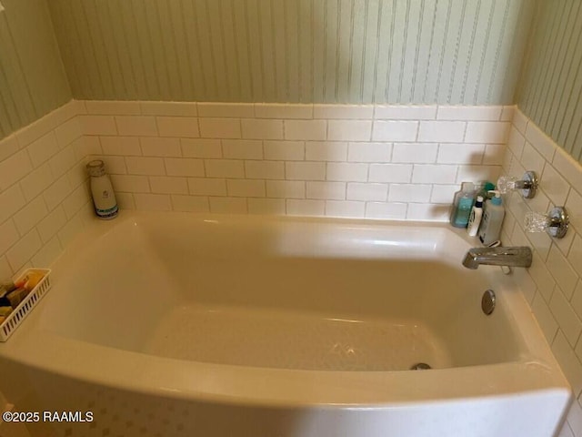 bathroom with wallpapered walls and a bath