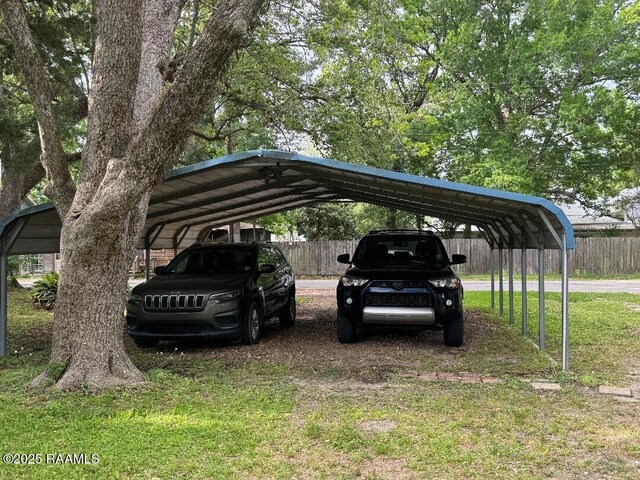 view of parking / parking lot with a detached carport and fence
