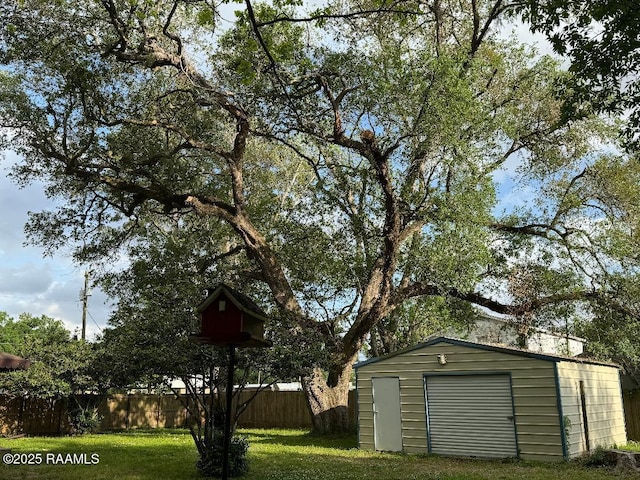 exterior space with a detached garage, fence, an outbuilding, and a shed