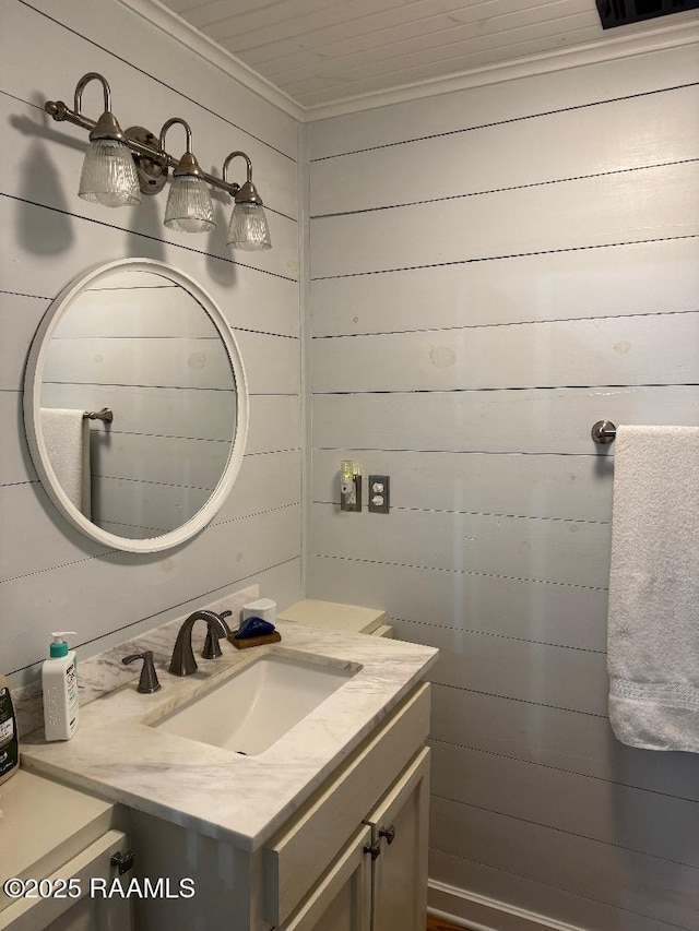 bathroom featuring crown molding, wood walls, and vanity