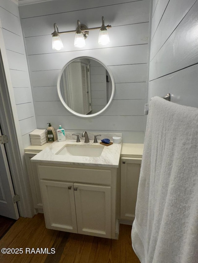 bathroom featuring wooden walls, vanity, and wood finished floors