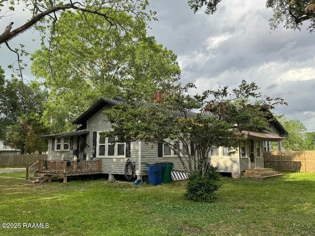 back of house with a lawn, a deck, and fence