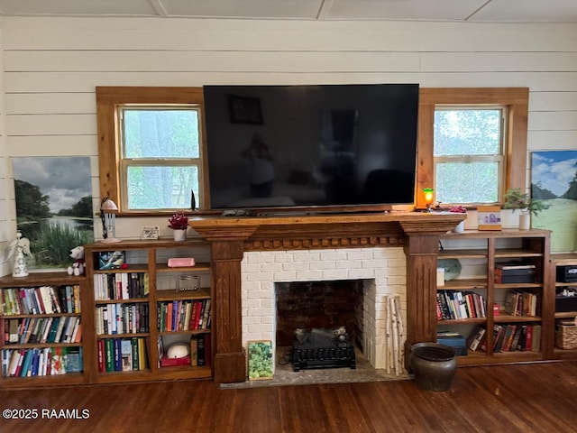 sitting room with a brick fireplace, wood walls, and wood finished floors