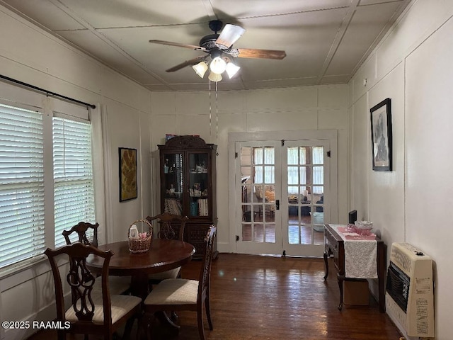 dining space with heating unit, wood finished floors, a decorative wall, french doors, and a ceiling fan