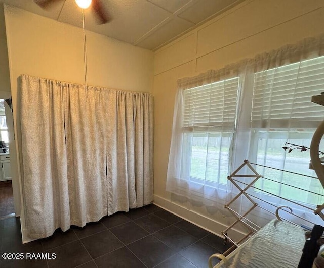 interior space featuring baseboards, ceiling fan, and dark tile patterned flooring