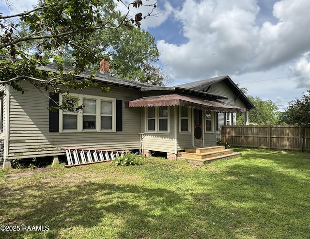 back of property featuring a lawn, fence, and a chimney