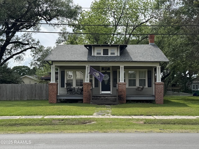 view of front of property with a porch, fence, a front yard, and a chimney