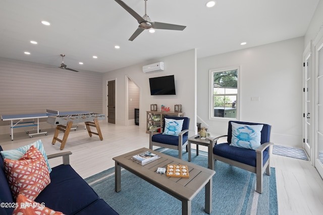 living room featuring a ceiling fan, recessed lighting, baseboards, light wood finished floors, and a wall unit AC