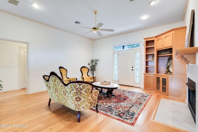 living area featuring recessed lighting, light wood-type flooring, a ceiling fan, visible vents, and ornamental molding