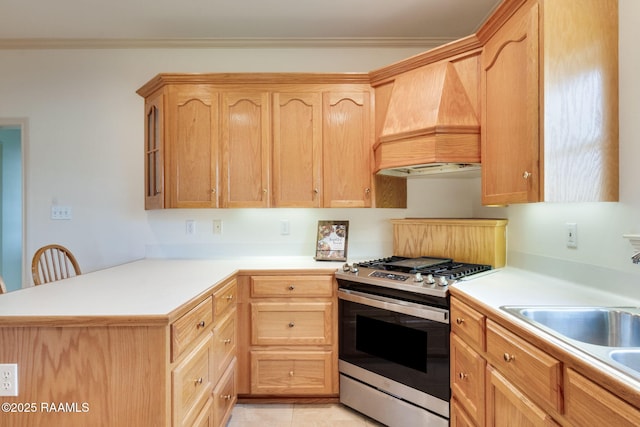 kitchen featuring light brown cabinetry, stainless steel gas range, a peninsula, and premium range hood
