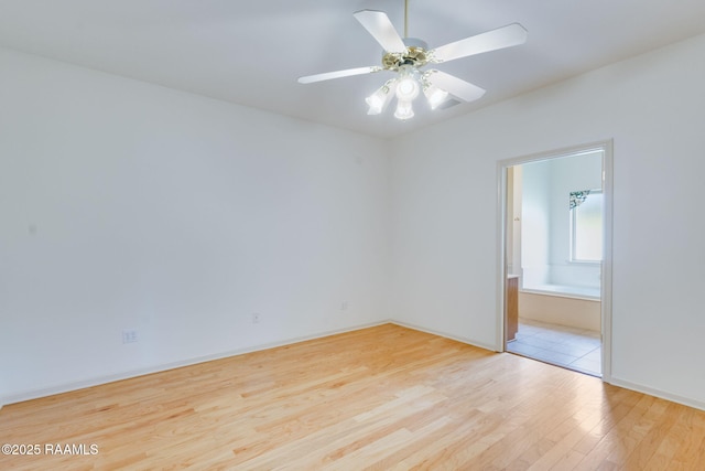 spare room with baseboards, wood finished floors, and a ceiling fan