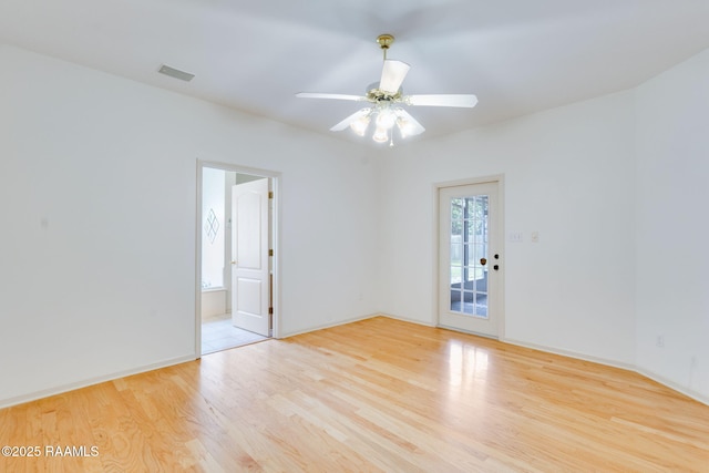 spare room featuring baseboards, visible vents, wood finished floors, and ceiling fan