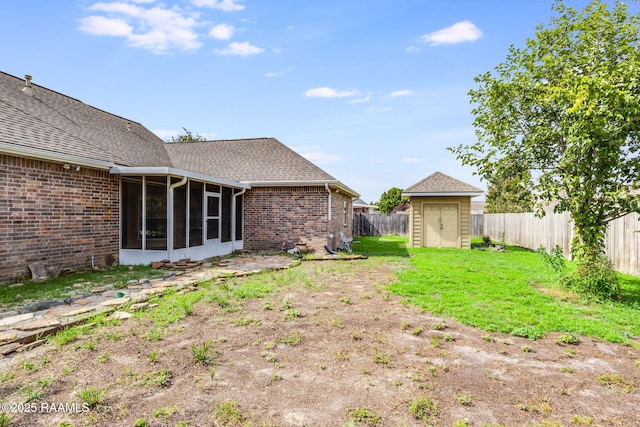 view of yard featuring a fenced backyard, a shed, an outbuilding, and a sunroom