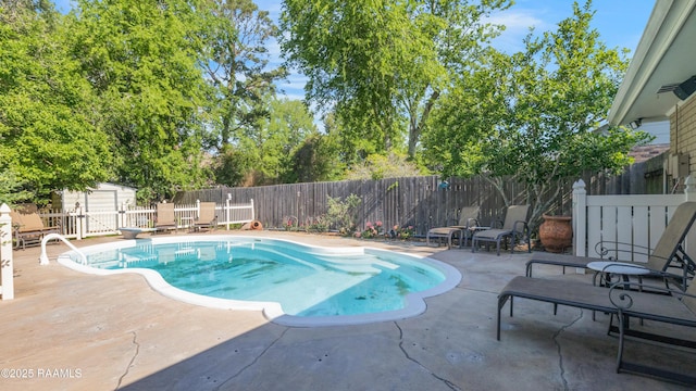 view of pool with a storage shed, a fenced backyard, a fenced in pool, a patio area, and an outdoor structure