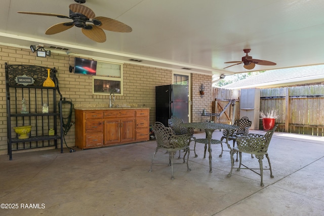 view of patio with a sink, fence, a ceiling fan, and visible vents