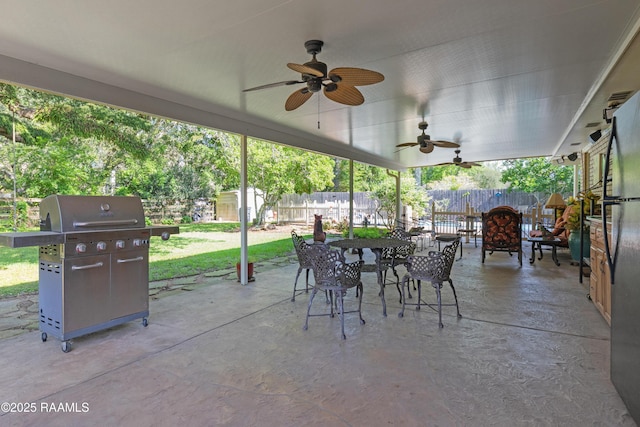 view of patio with a grill, a ceiling fan, a fenced backyard, and a storage unit