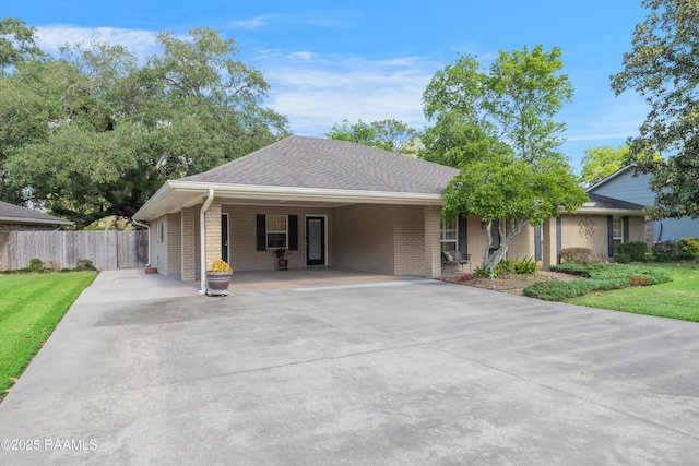 view of front facade featuring driveway, a carport, brick siding, fence, and a front lawn