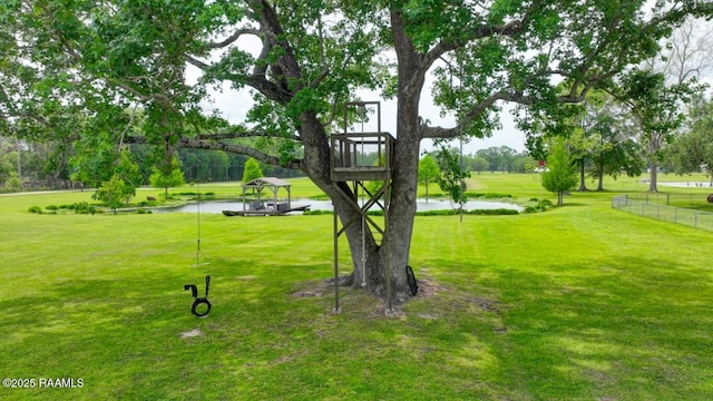 surrounding community with a lawn, a water view, and fence