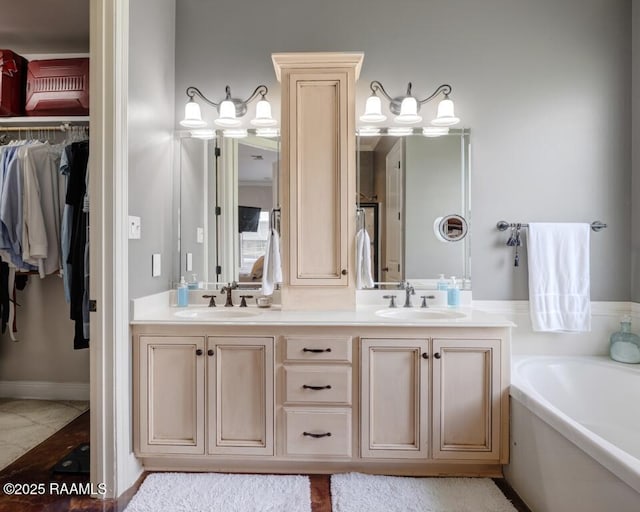 bathroom with a bath, a sink, a spacious closet, and double vanity