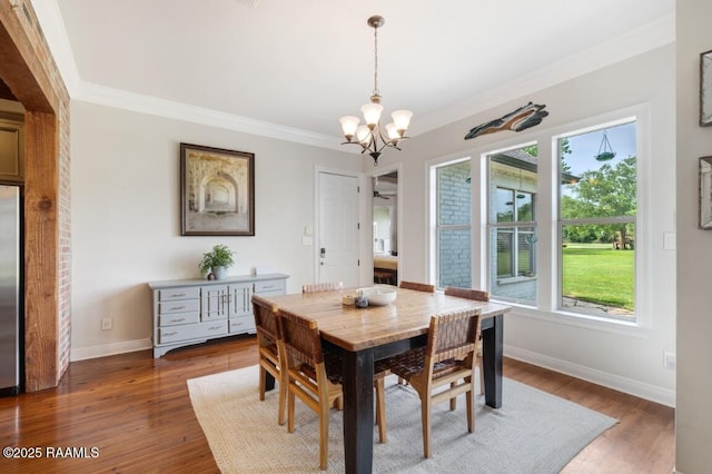 dining room featuring a chandelier, plenty of natural light, crown molding, and baseboards
