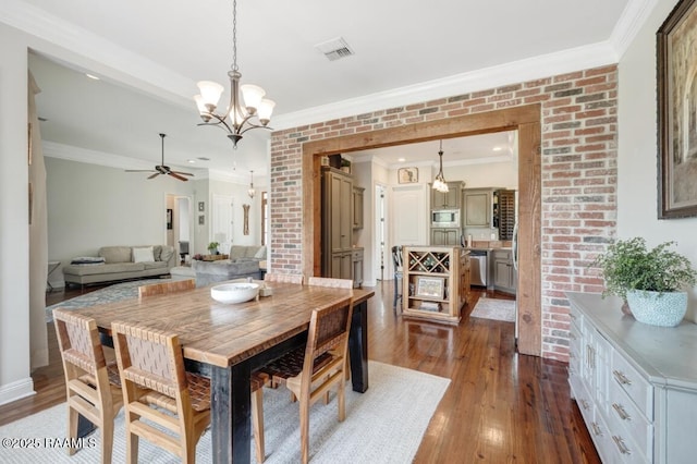 dining room with crown molding, visible vents, dark wood-style flooring, and ceiling fan with notable chandelier