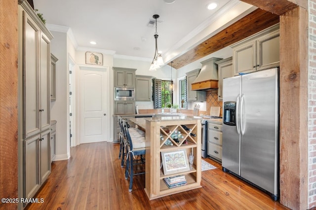 kitchen with a kitchen bar, hardwood / wood-style floors, appliances with stainless steel finishes, and custom exhaust hood