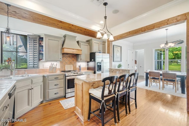kitchen featuring a sink, an inviting chandelier, stainless steel appliances, light wood finished floors, and custom range hood