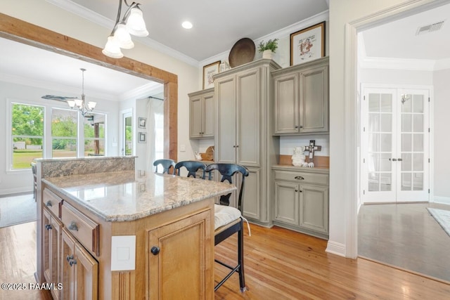 kitchen with a kitchen breakfast bar, visible vents, light wood-style floors, and a chandelier
