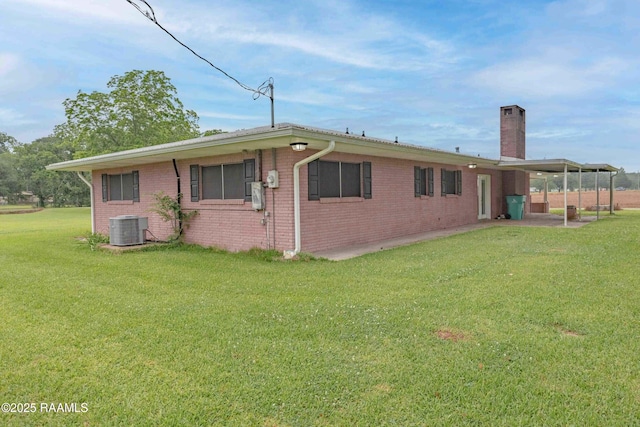 1706 Fuselier Rd, Arnaudville, LA 70512 - back of house with central AC, a chimney, brick siding, a lawn, and a carport