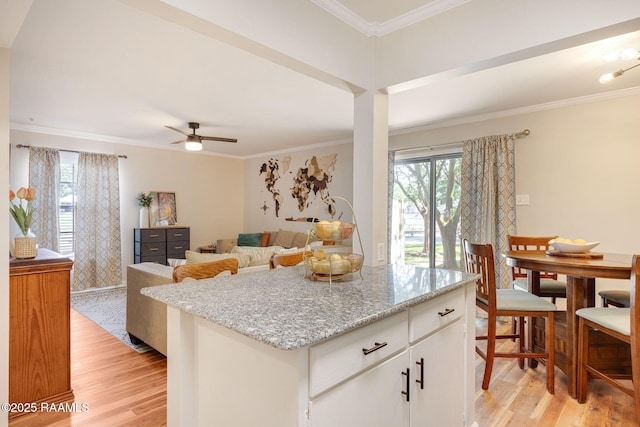 211 Versailles Blvd Unit 5, Lafayette, LA 70501 - kitchen featuring white cabinets, ceiling fan, light wood-style floors, a kitchen island, and ornamental molding