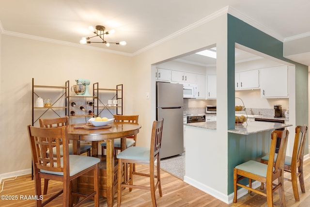 211 Versailles Blvd Unit 5, Lafayette, LA 70501 - dining area with light wood-type flooring, baseboards, crown molding, and an inviting chandelier
