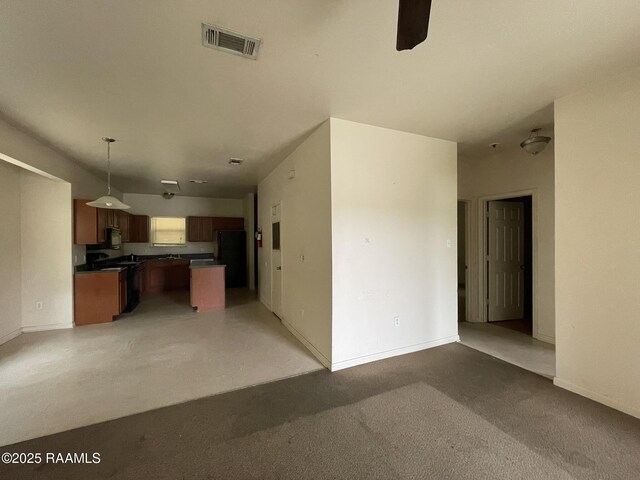 unfurnished living room with baseboards, a ceiling fan, and visible vents