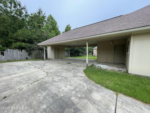 view of parking / parking lot with concrete driveway and fence