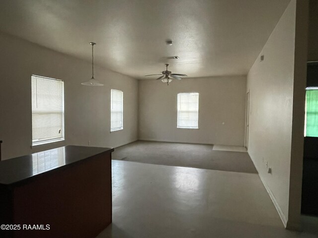 interior space featuring ceiling fan, concrete flooring, and baseboards