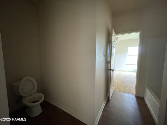 bathroom with baseboards, wood finished floors, and toilet