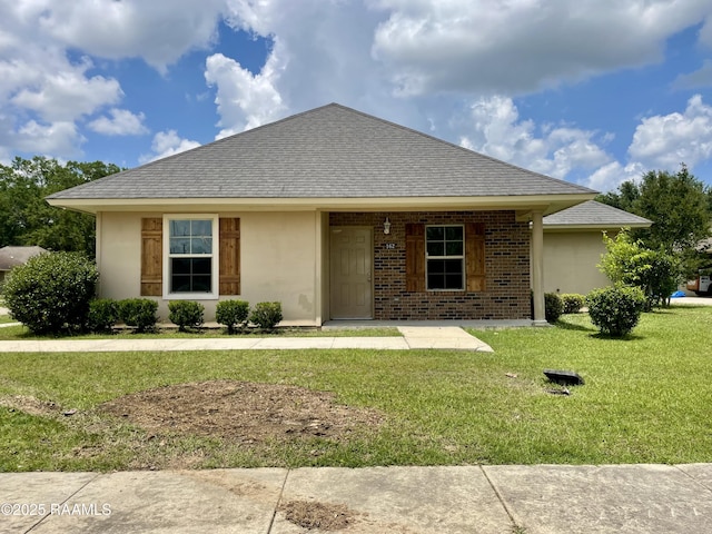 single story home with stucco siding, a front yard, a shingled roof, and brick siding