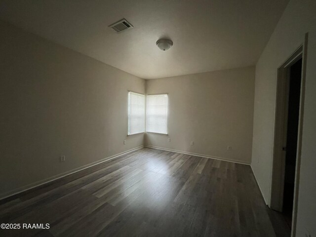 spare room with baseboards, dark wood-type flooring, and visible vents