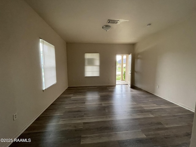 spare room with dark wood finished floors, baseboards, and visible vents