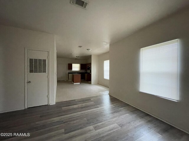 unfurnished living room with baseboards, wood finished floors, and visible vents