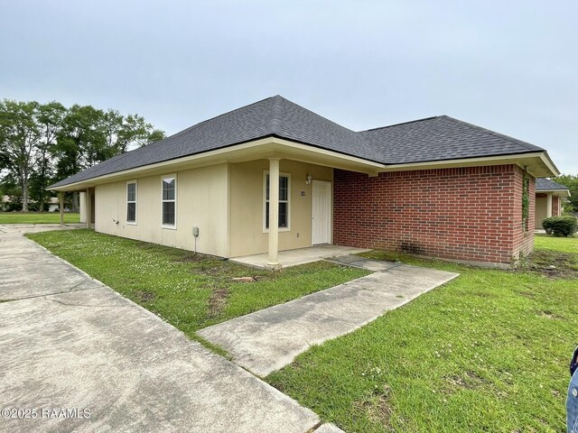 view of side of home featuring a lawn and a shingled roof