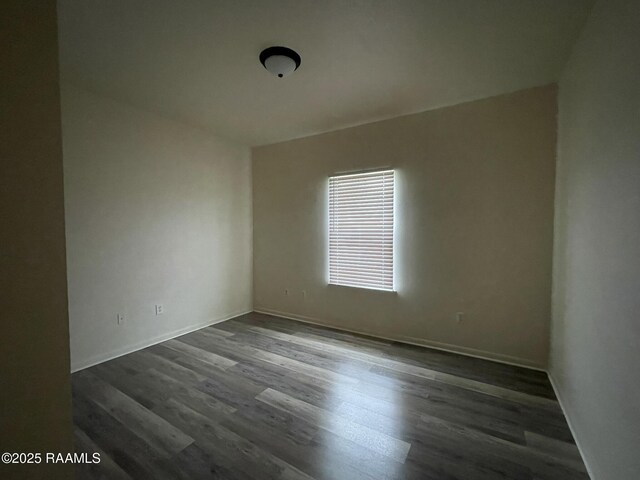 spare room with baseboards and dark wood finished floors