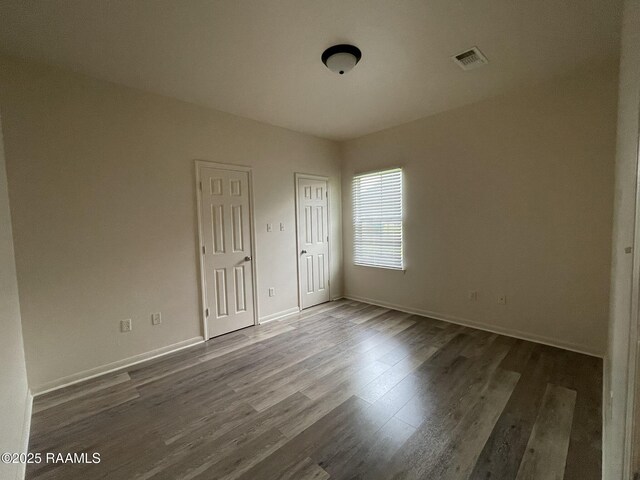unfurnished bedroom featuring wood finished floors, visible vents, and baseboards